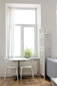 Biały stół i krzesła w pokoju z oknem w obiekcie White Door Apartments Heart of Odessa 1 w Odessie