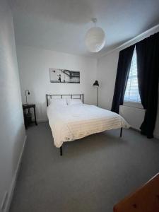 1 dormitorio con cama blanca y ventana en Two bedroom ground floor apartment with garden, en Falkirk
