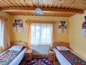 two beds in a room with a window at Casa Muntean in Vadu Izei