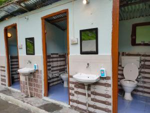 La salle de bains est pourvue de 2 toilettes et de 2 lavabos sur le mur. dans l'établissement Himtrek Camps Jibhi, à Jibhi