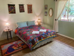 1 dormitorio con 1 cama con una manta colorida y una ventana en Karma Backpackers, en Kestell