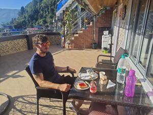 a man sitting at a table with a plate of food at Paul's stay in Darjeeling