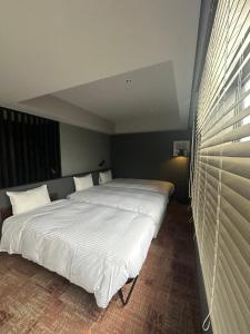 1 Schlafzimmer mit 2 Betten und weißer Bettwäsche in der Unterkunft LOF HOTEL Shimbashi in Tokio