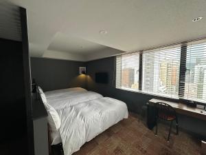 Schlafzimmer mit einem Bett, einem Schreibtisch und Fenstern in der Unterkunft LOF HOTEL Shimbashi in Tokio