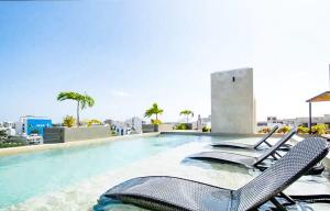 a swimming pool with chairs on the roof of a building at Joya de la Zazil 20 Av ROOFTOP POOL Walk to Playa Mamitas Coco Beach & 5 in Playa del Carmen