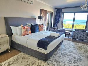 a bedroom with a large bed with a view of the ocean at The Whale's Tale Guesthouse in Hermanus