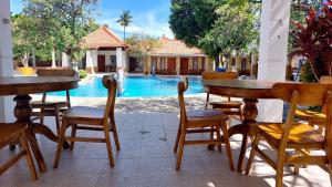 a patio with tables and chairs in front of a pool at Grand Melka Hotel in Lovina