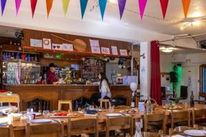 um restaurante com mesas de madeira e uma mulher sentada num bar em Gite de la Draye em Crots