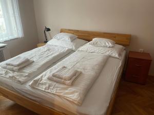 2 bedden in een slaapkamer met witte lakens en handdoeken bij Platán Apartman in Marcali