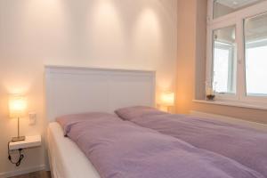 Bett in einem Zimmer mit zwei Lampen und einem Fenster in der Unterkunft Ferienwohnung Pusteblume - Villa Stranddistel in Binz