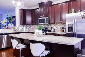 a kitchen with a large island with white chairs at Large MD Townhome mins to UMD & DC Parking in Greenbelt