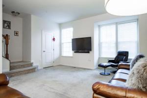 sala de estar con sofá y TV de pantalla plana en Large MD Townhome mins to UMD & DC Parking, en Greenbelt