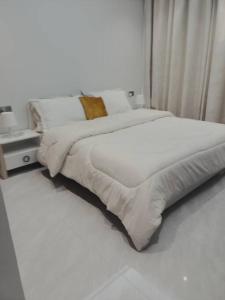 een witte slaapkamer met een groot bed met witte lakens bij Quite and Cozy in Seeb