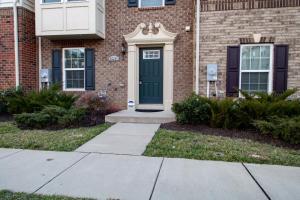 a brick house with a green door and a sidewalk at Large MD Townhome mins to UMD & DC Parking in Greenbelt