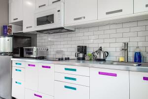 a kitchen with white cabinets and pink and blue handles at Eastern Market Carriage house efficiency PRIVACY in Washington, D.C. +5 photos