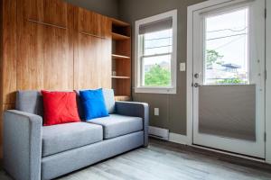 a gray couch with colorful pillows in a living room at Eastern Market Carriage house efficiency PRIVACY in Washington, D.C.