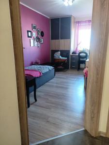um quarto com uma cama e uma parede rosa em Apartament Wichrowe Wzgórze Olsztyn em Olsztyn