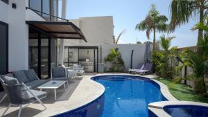 un patio trasero con piscina, sillas y una casa en LUX amazing villa with private pool, en Eilat