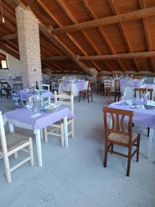 La Locanda Del Molino في Fortunago: غرفة بها طاولات بيضاء وكراسي بها مفارش أرجوانية
