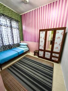 sala de estar con sofá azul y pared rosa en Homestay Hitech Kulim Islam Guest Only en Kulim