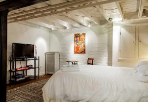 a bedroom with a white bed and a flat screen tv at The E St Retreat Lovely 3-BR Nestled between H St & Eastern Market in Washington, D.C.