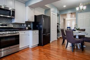 a kitchen with white cabinets and a black refrigerator at NoMA 3BR Townhome - UnionMarket H St Streetcar in Washington, D.C.