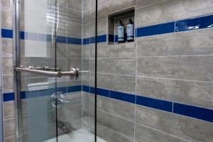 a bathroom with a shower with blue and white tiles at NoMA 3BR Townhome - UnionMarket H St Streetcar in Washington, D.C. +13 photos