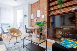 a living room with a brick wall and a tv at Classy 1-BR Flat Nestled Between Dupont & Logan in Washington, D.C.