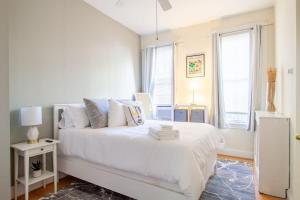 a white bedroom with a white bed and windows at Classy 1-BR Flat Nestled Between Dupont & Logan in Washington, D.C.