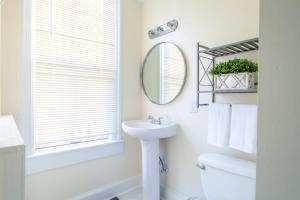 a white bathroom with a sink and a mirror at Classy 1-BR Flat Nestled Between Dupont & Logan in Washington, D.C.