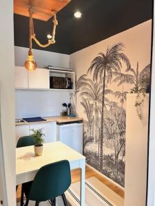 a kitchen with a table with a palm tree mural at La suite avec jacuzzi in Saint-Martin-de-Londres