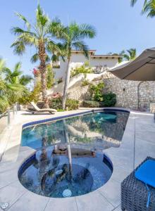 a swimming pool with palm trees and a building at Infinite views of Palmilla beach and East Cape in San José del Cabo