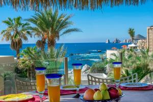 einen Tisch mit einer Schale Obst und Gläsern Orangensaft in der Unterkunft Views to El Arco, Famous Cabo San Lucas bay rock formation in El Pueblito