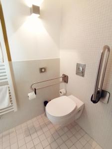 a bathroom with a toilet with a light above it at Nymphe Strandhotel & Apartments in Binz