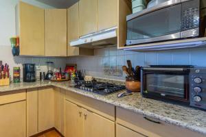 a kitchen with a microwave and a stove top oven at Villa Calafia Spacious Home w Private Tennis in Cabo San Lucas