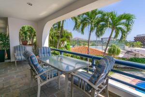 a balcony with a table and chairs and palm trees at Villa Calafia Spacious Home w Private Tennis in Cabo San Lucas