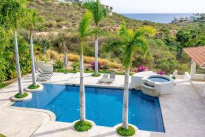 a swimming pool with palm trees and the ocean at Las Terrazas Cerro Colorado in El Bedito