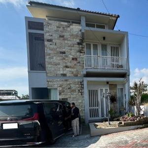 un hombre parado frente a una casa con su coche en Casa Rani Batu Malang Villa, en Batu