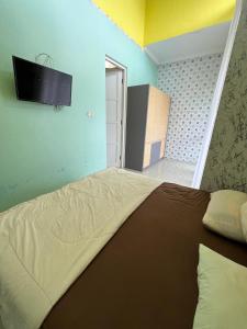 a bedroom with a bed with a television on the wall at Casa Rani Batu Malang Villa in Batu