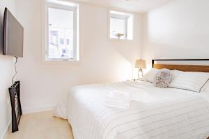 a white bedroom with a bed and a tv at Bright & Cozy 1-BR Alcove in Bloomingdale in Washington, D.C.