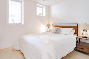 a white bedroom with a large white bed and two windows at Bright & Cozy 1-BR Alcove in Bloomingdale in Washington, D.C.