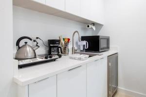 a white kitchen with a microwave and a stove at Bright & Cozy 1-BR Alcove in Bloomingdale in Washington, D.C.