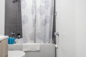 a bathroom with a shower with a white shower curtain at Bright & Cozy 1-BR Alcove in Bloomingdale in Washington, D.C. +10 photos