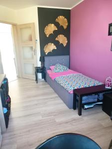 um quarto com uma cama e uma parede rosa em Apartament Wichrowe Wzgórze Olsztyn em Olsztyn