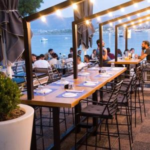un grupo de personas sentadas en mesas en un restaurante en Porto Rafti Hideaway, en Porto Rafti