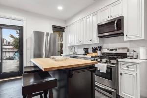 a kitchen with stainless steel appliances and white cabinets at H St DC Haven 4-BR Homestay in Washington, D.C.