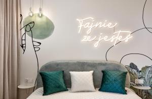 a room with a couch with green pillows and a sign at Premium City Apartments in Bydgoszcz