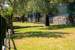 park z drzewami i kamienną ścianą w obiekcie Campeggio Toscolano w mieście Toscolano Maderno