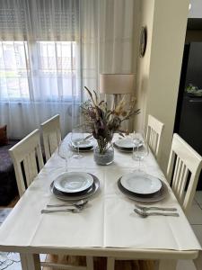 - une table blanche avec des assiettes et des verres à vin dans l'établissement Sol Apartments - 2 Bedrooms, à Shkodër