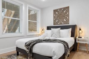 a bedroom with a large bed with white walls and windows at Excellent 2-BR Condo in Hip Area of DC in Washington, D.C.